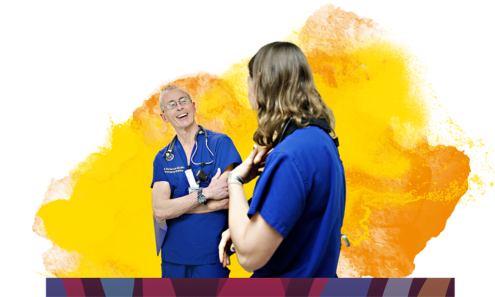 Two healthcare professionals in blue scrubs smiling and talking against a colorful background.