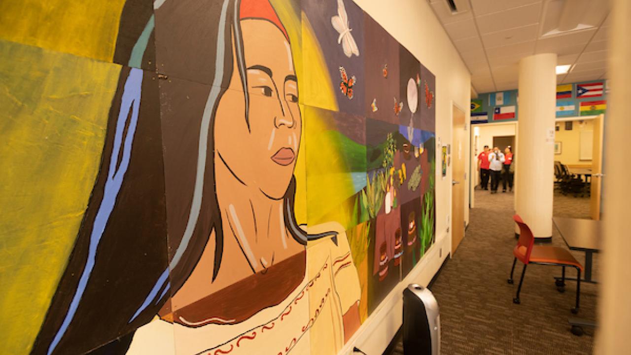 Mural depicting a woman with long hair and vibrant colors in a hallway setting.