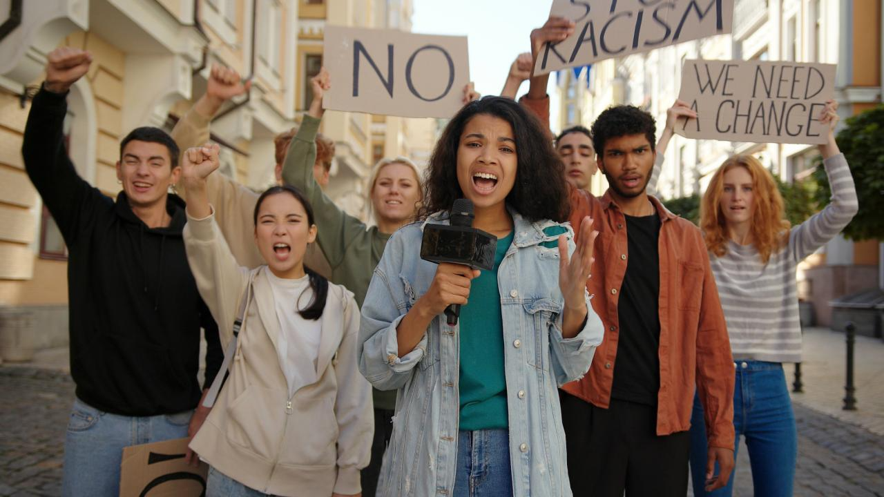 A diverse group of young activists protesting, holding signs and raising fists in solidarity.