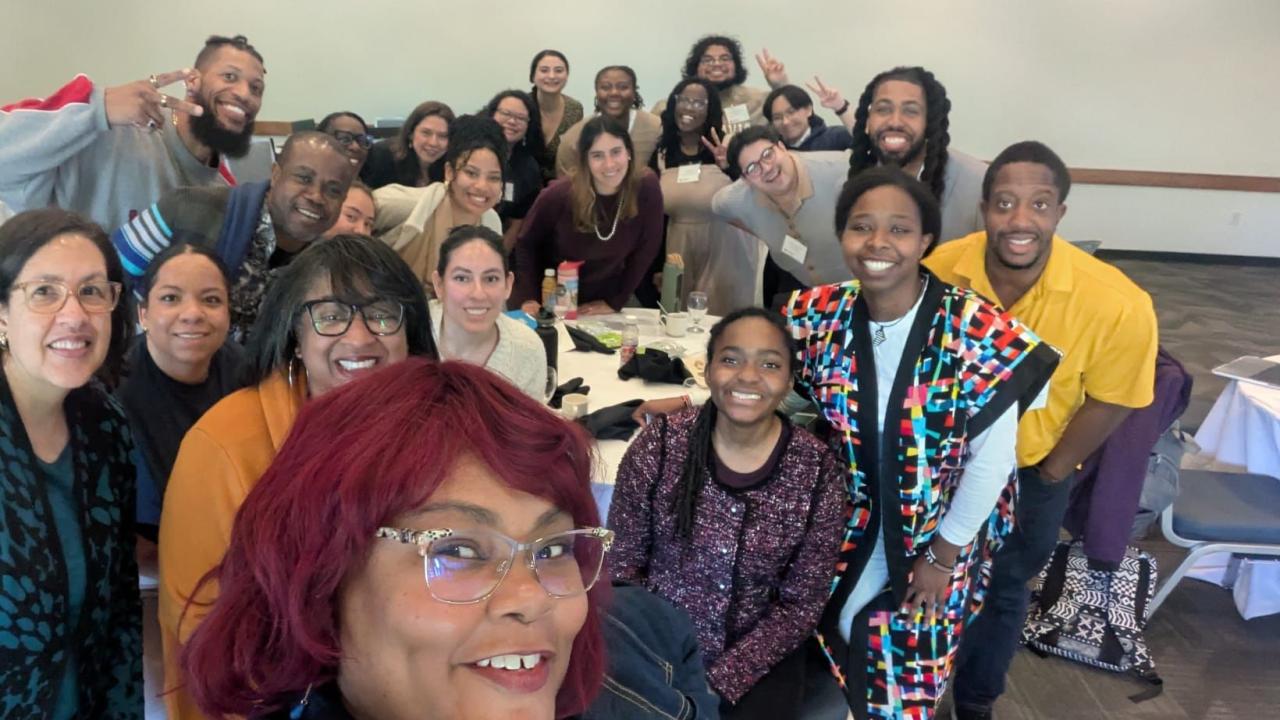 Group selfie in conference room; smiling adults.