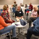 Woman in black top sits at center of book club group.