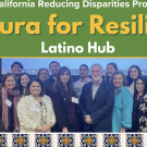 Group photo of Latino Hub team in front of green 'Cultura for Resilience' banner